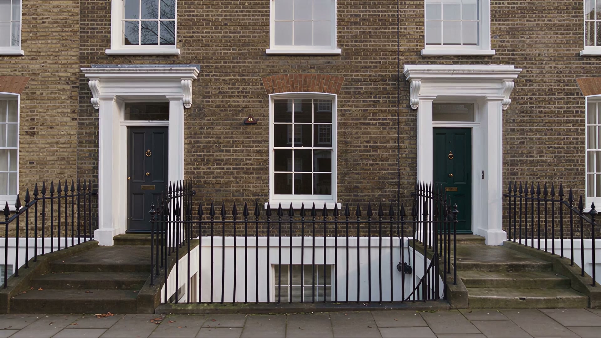 A Georgian brick terrace with two dark front doors, white sash windows and black railings