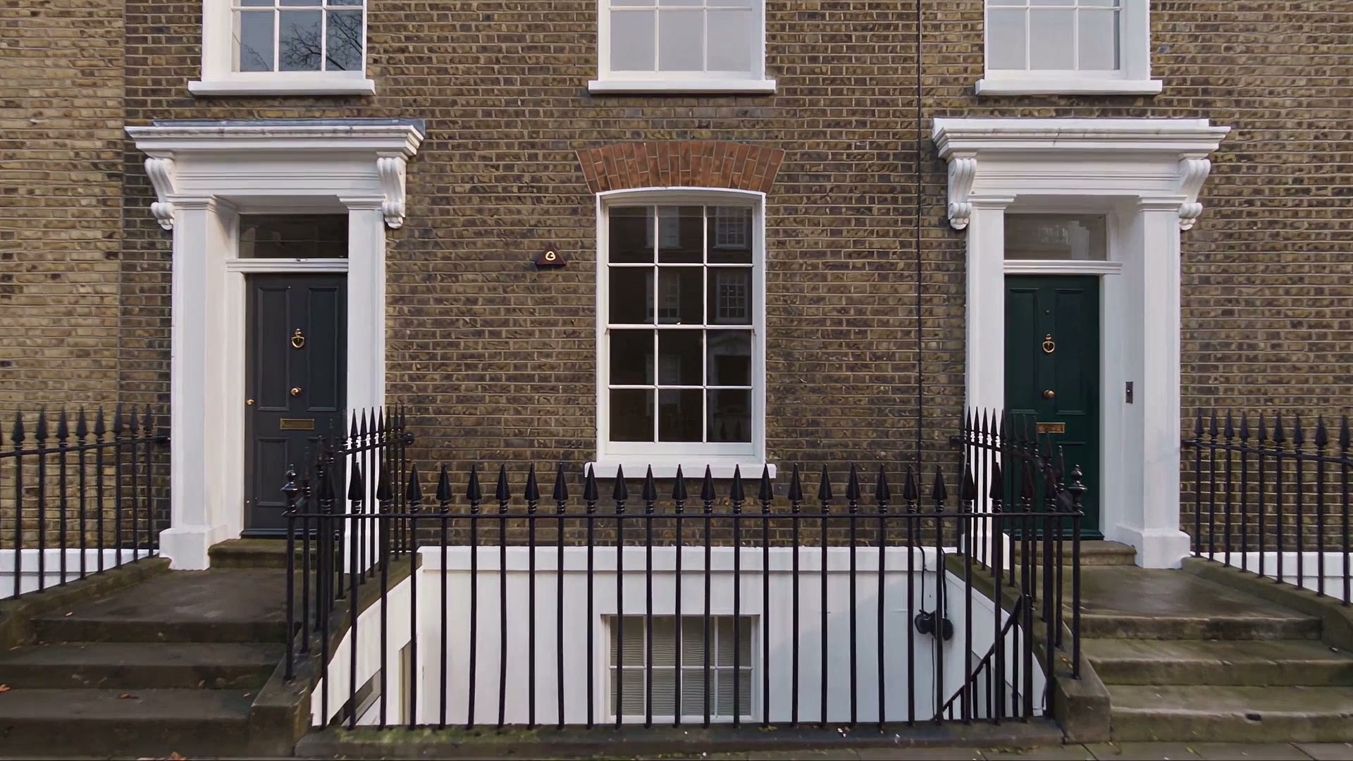 A Georgian brick facade with a white sash window and a dark green front door