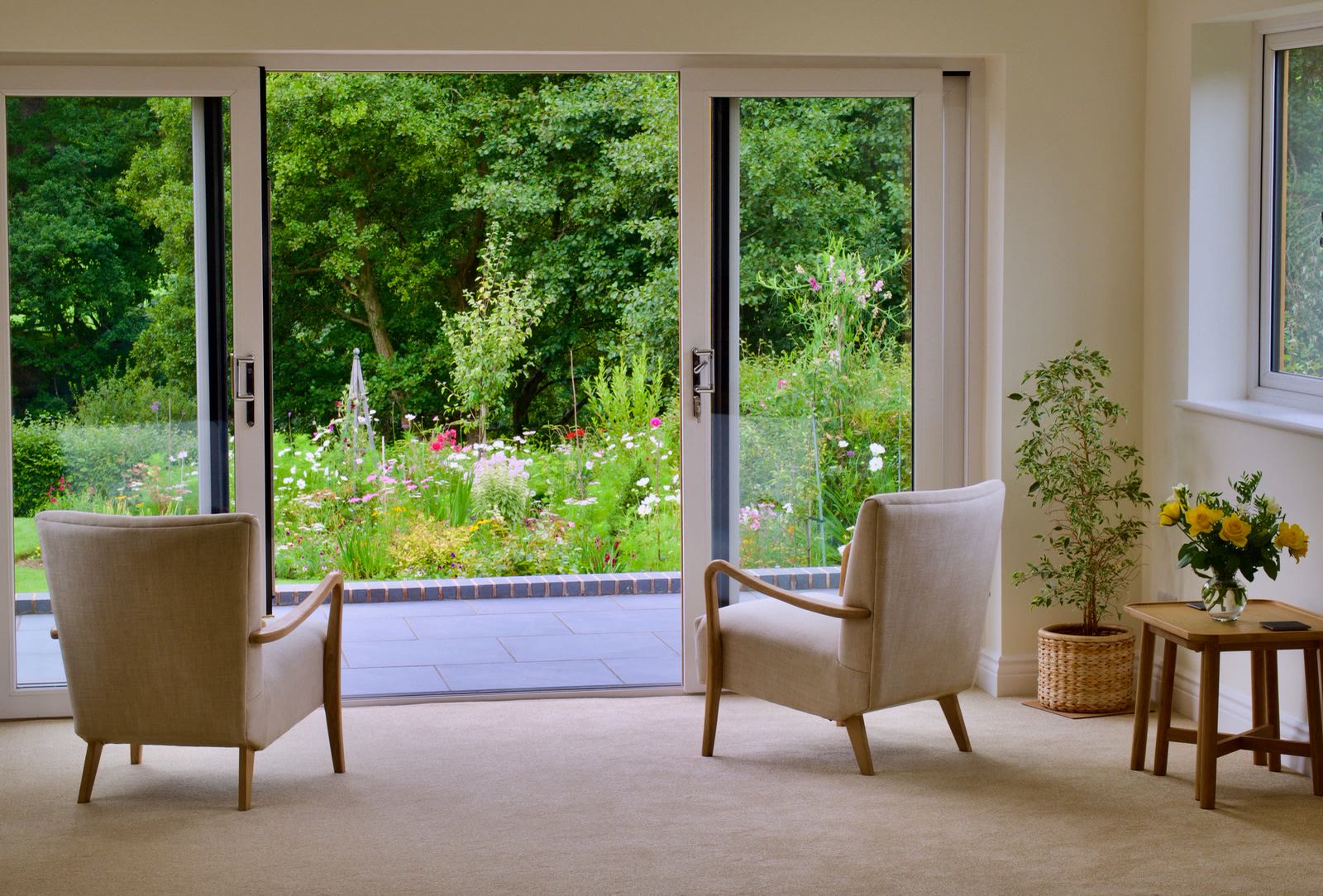 Two armchairs by large sliding glass doors looking onto greenery
