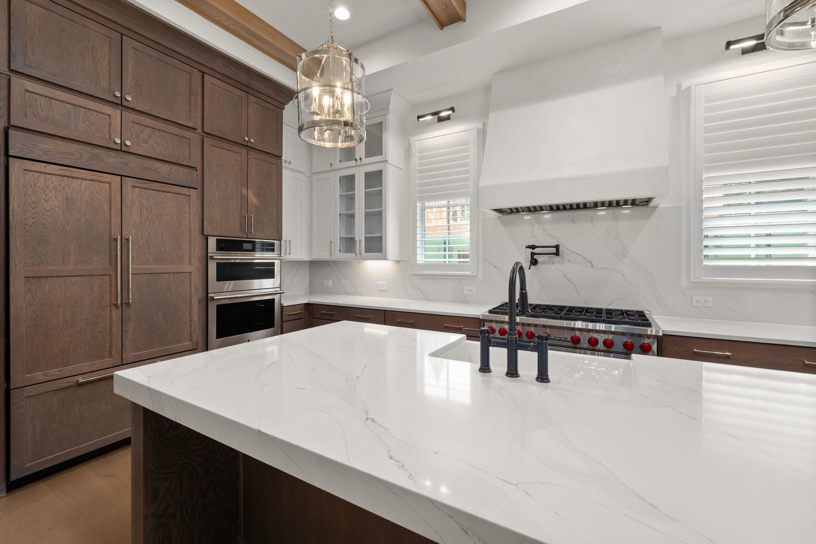 A kitchen with a marble island and wooden cabinetry