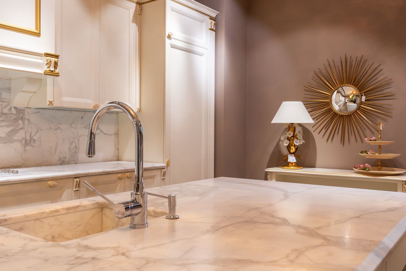A sink and tap on a marble counter in a white kitchen