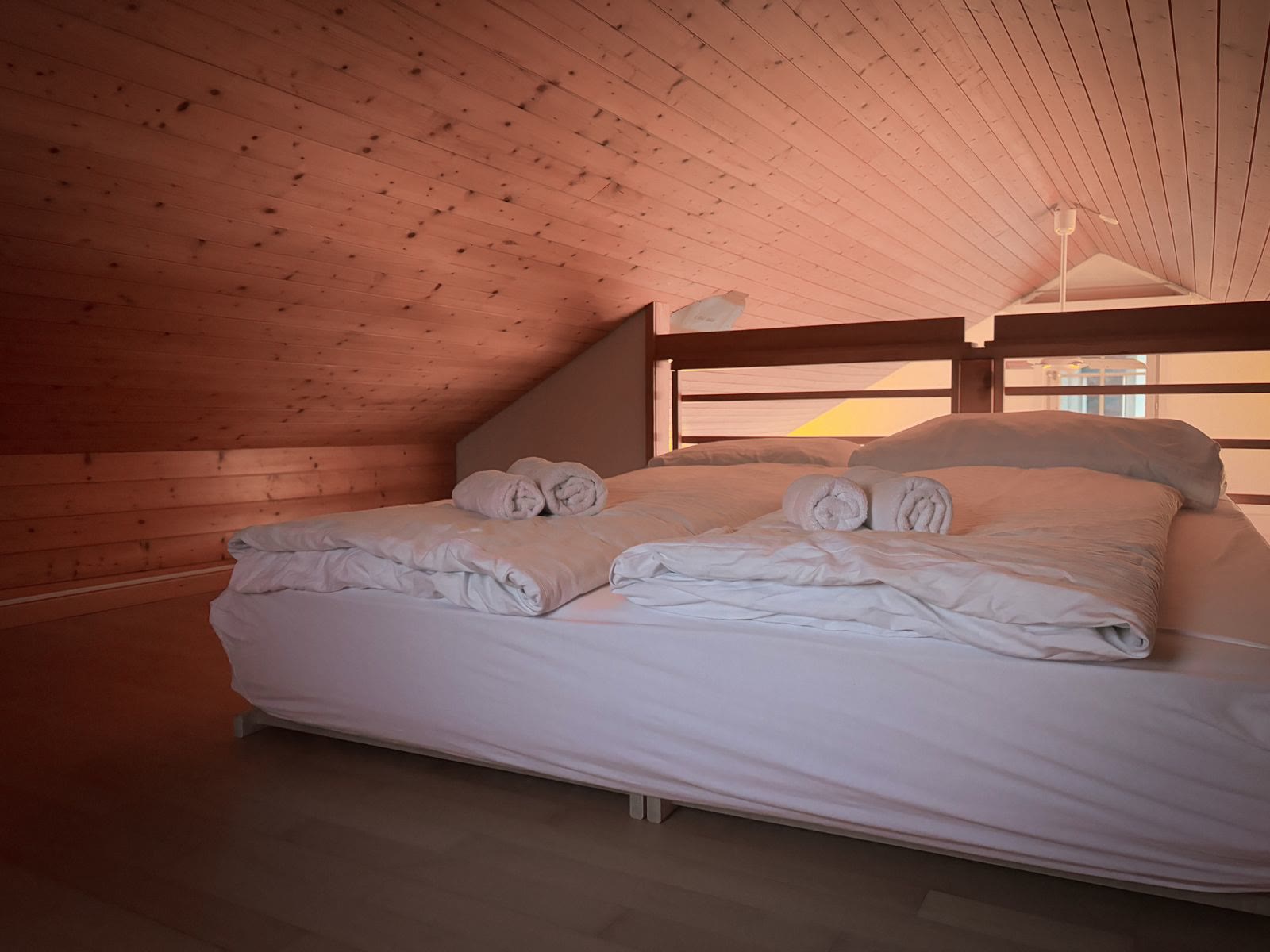 A loft bedroom with a wooden ceiling and fresh linen
