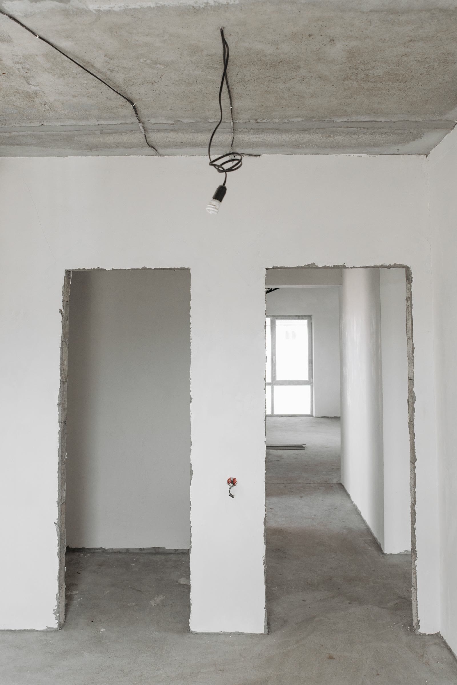 An unfinished room with white plastered walls and an exposed ceiling