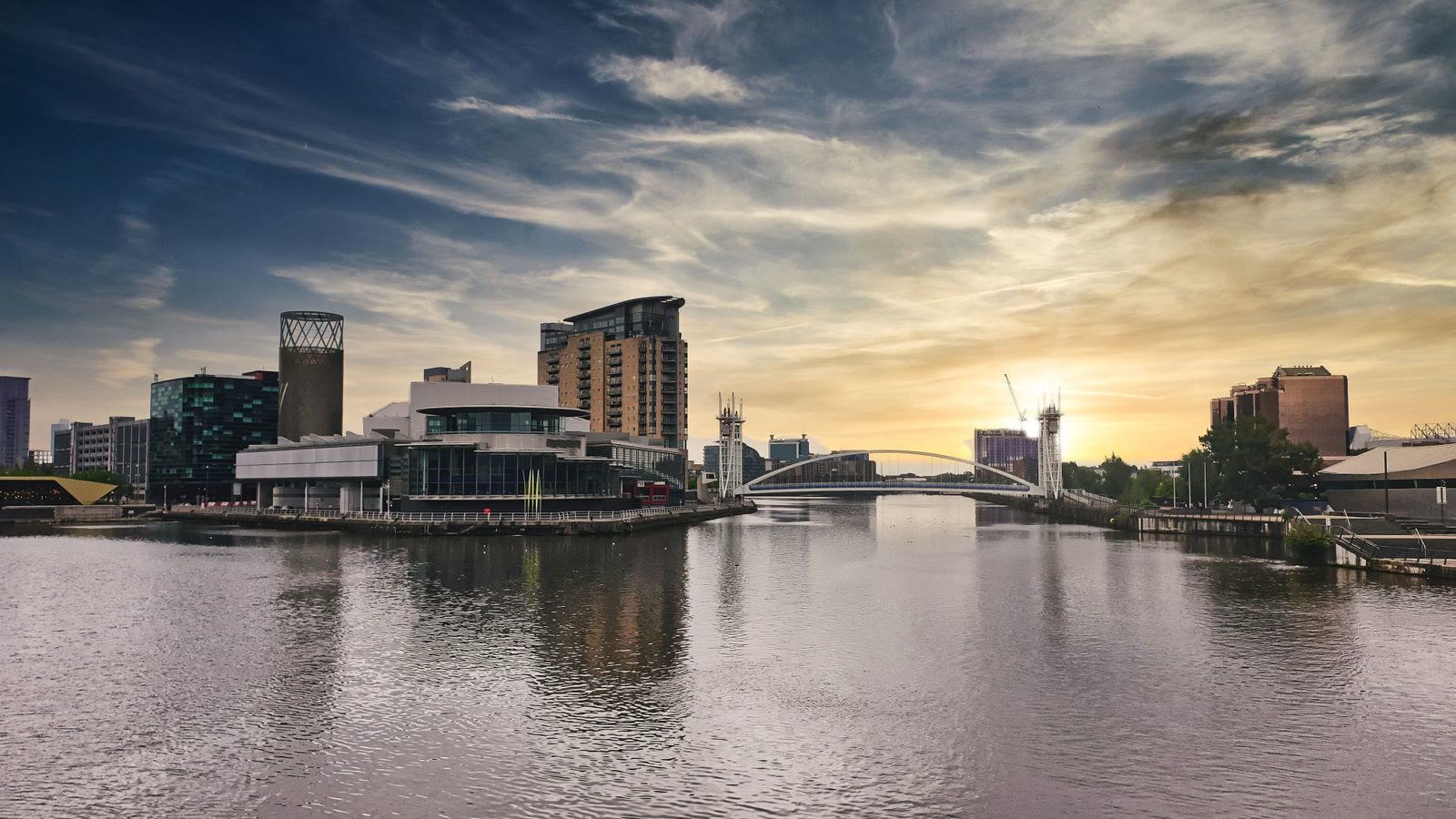 Salford Quays at sunset with modern buildings reflected in the water