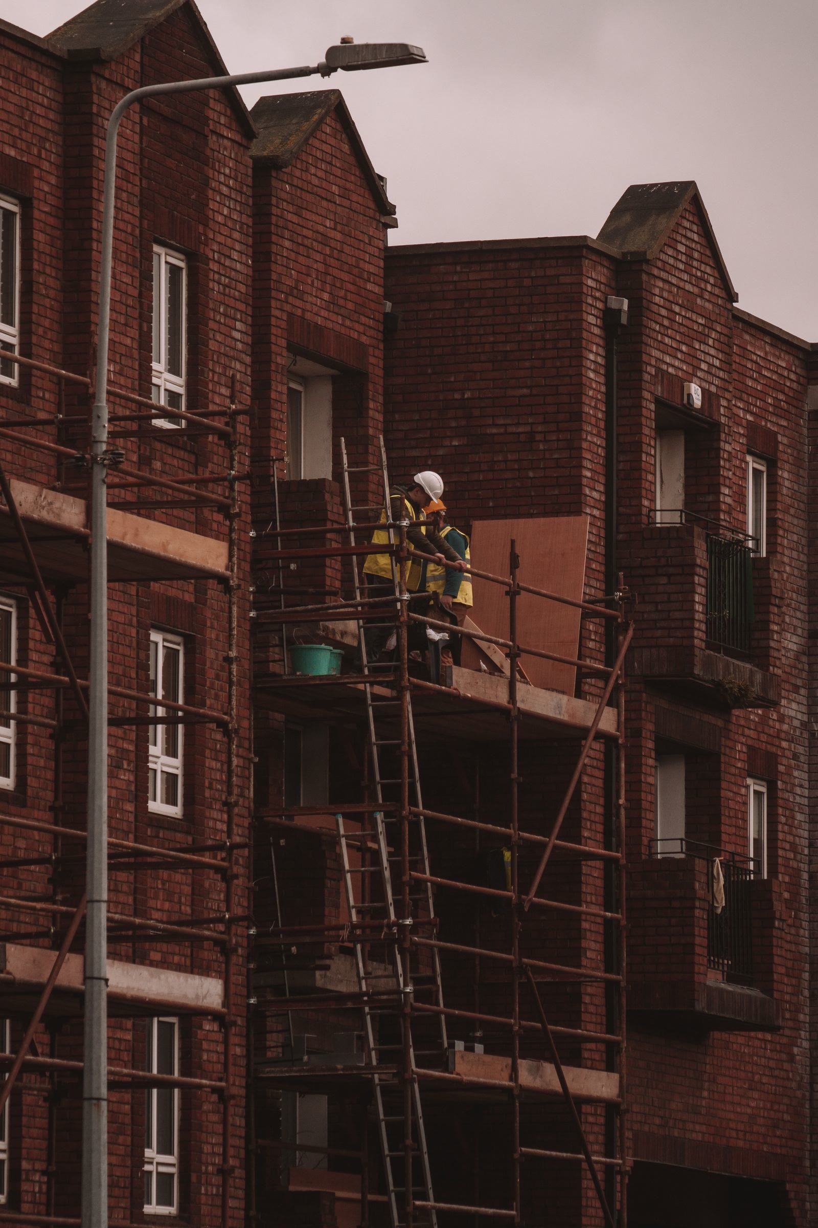Workers on scaffolding renovating a brick residential building